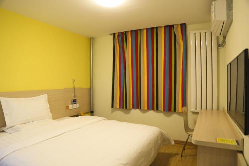 大同的住宿－7天連鎖酒店大同火車站店，卧室配有白色的床和色彩缤纷的窗户。