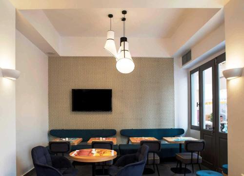 a dining room with tables and chairs and a tv at Athena hotel in Nafplio
