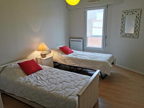 deux lits dans une chambre avec une fenêtre dans l'établissement LES DUNES DE BLOSSAC 100m de la plage avec garage, à Les Sables-dʼOlonne
