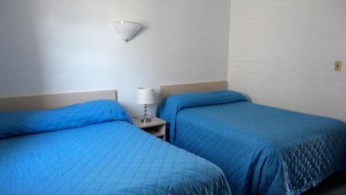 2 Betten in einem Zimmer mit blauer Bettwäsche in der Unterkunft Golden Rail Motel in North Wildwood