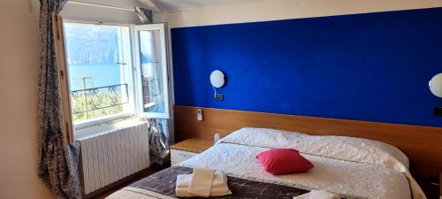 a bedroom with a blue wall and a bed with a red pillow at Hotel Bellavista Meublè in Monte Isola