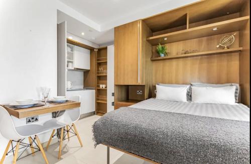 1 dormitorio con cama, escritorio y cocina en West One Studio Apartments, en Gibraltar