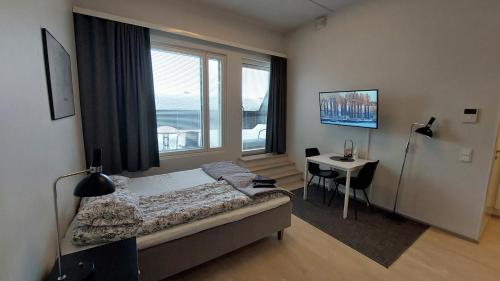 1 dormitorio con cama, escritorio y ventana en Kotimaailma Apartments Vapaudenkatu 48-50 B51, en Jyväskylä