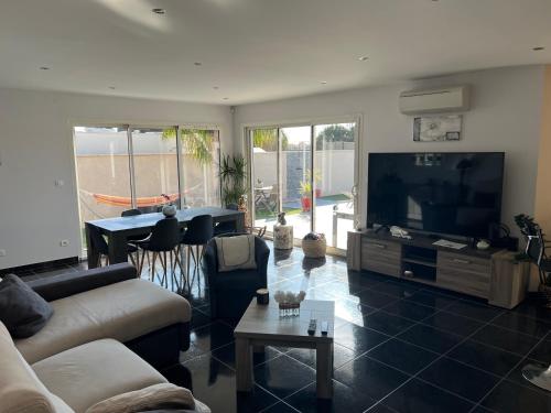 un salon avec un canapé et une télévision à écran plat dans l'établissement Villa 3 chambres avec Piscine, à Saint-Laurent-de-la-Salanque