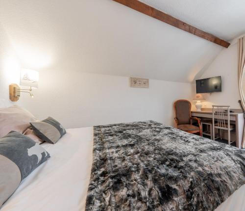 a bedroom with a large bed and a desk at Logis Hôtel et Spa Le Christiania in La Salle Les Alpes