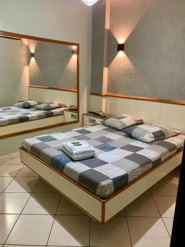 1 dormitorio con 2 camas y un espejo grande en Hotel Glória en Niterói