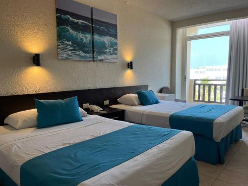 Habitación de hotel con 2 camas y almohadas azules en Howard Johnson by Wyndham Veracruz, en Veracruz