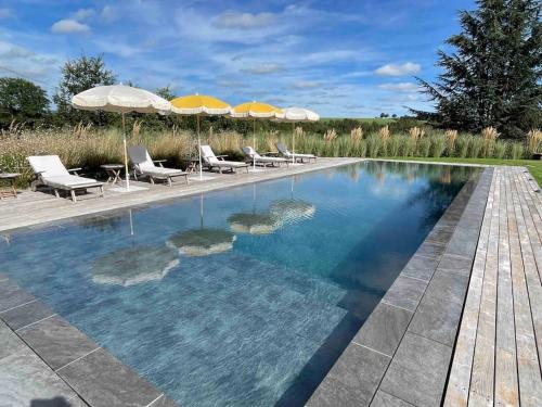une grande piscine avec chaises et parasols dans l'établissement La Roulière en Aubrac, à Montpeyroux