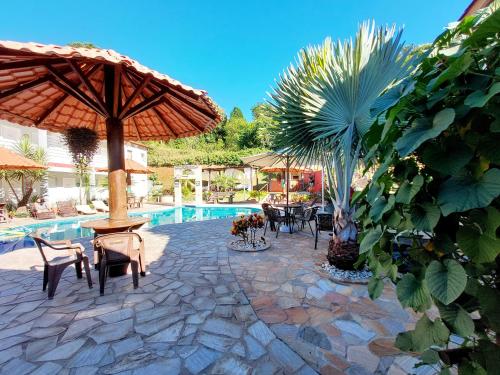 a patio with an umbrella and chairs and a pool at Pousada Pompeia in Socorro
