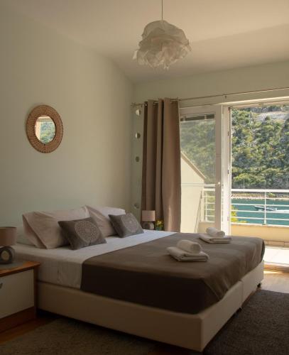 a bedroom with a large bed with a large window at Villa Casia in Mokošica