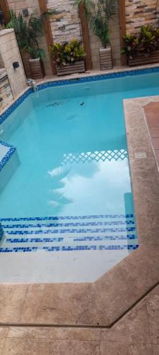 una gran piscina con azulejos azules. en Villa Isabel, villa entera, piscina, cerca embajada USA, en Santo Domingo