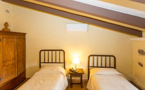 a bedroom with two beds and a table with a lamp at Turismo Rural Can Massot in Darnius