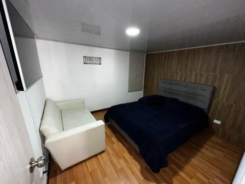 a small bedroom with a bed and a white chair at Apartaestudio calido y bien ubicado en Manizales in Manizales