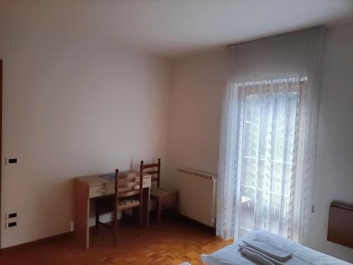 1 dormitorio con escritorio, mesa y ventana en ALBERGO AL LAGO, en Imer