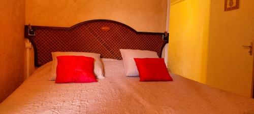 ein Schlafzimmer mit einem Bett mit zwei roten Kissen in der Unterkunft Villa d'une chambre avec piscine privee terrasse amenagee et wifi a Petit Bourg in Petit-Bourg