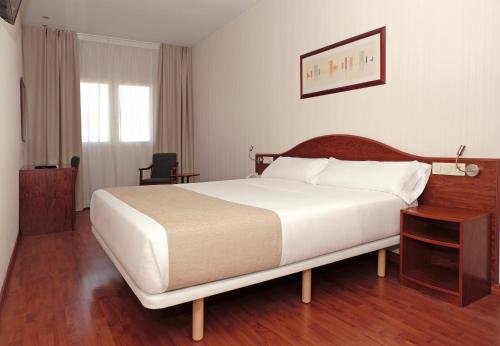 a bedroom with a large white bed and a table at Hotel Belcaire in Vall de Uxó