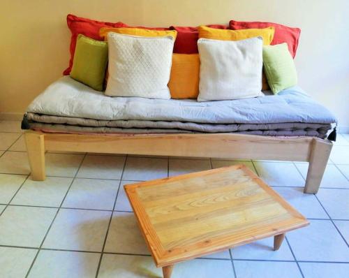 un banc avec des oreillers colorés et une table dans l'établissement F 1 COCOON au coeur de Prades, à Prades