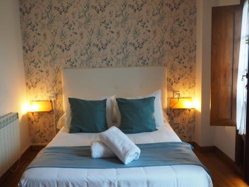 - une chambre dotée d'un lit avec deux oreillers et d'un papier peint à fleurs dans l'établissement LA CASINA DEL CARRIL, à Colunga