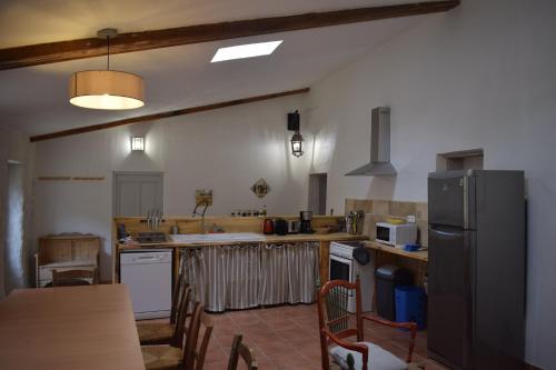 Il comprend une cuisine équipée d'un réfrigérateur et d'une table avec des chaises. dans l'établissement Mas du Pont, à Saint-Jean-de-Maruéjols-et-Avéjan