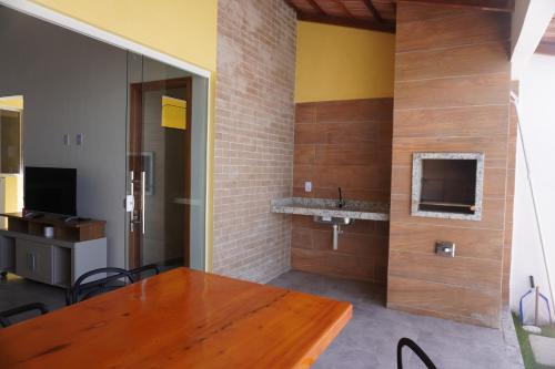 a dining room with a wooden table and a television at ESTRELA DO MAR in Prado