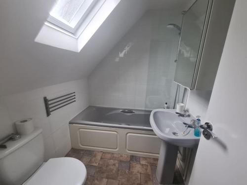 a bathroom with a sink and a toilet and a bath tub at Split level luton town center flat in Luton