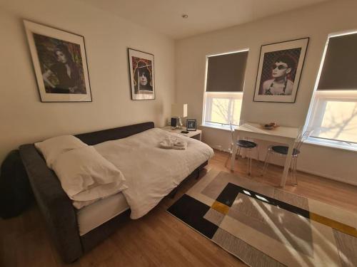a bedroom with a bed and a desk and two windows at Split level luton town center flat in Luton