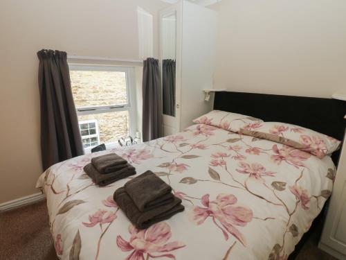 a bedroom with a bed with pink flowers on it at Jasmine Cottage in Richmond