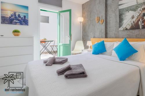 a bedroom with a large white bed with blue pillows at Casa Design In the center by iRent Fuerteventura in Corralejo