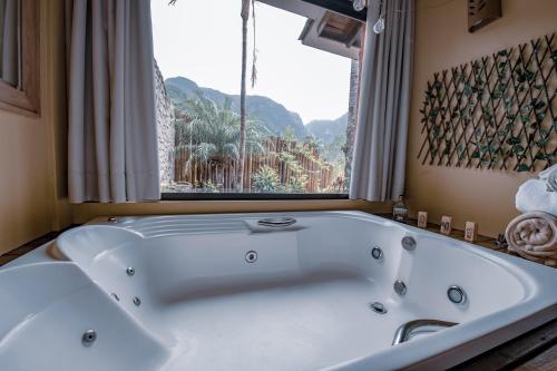 a large white tub in a bathroom with a window at Refúgio Ecológico Pedra Afiada in Praia Grande