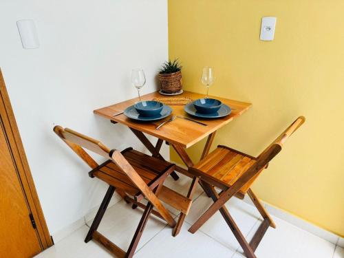a wooden table with two chairs and two wine glasses at Apto no Coração de Serra Negra / 50m da Rodoviaria in Serra Negra