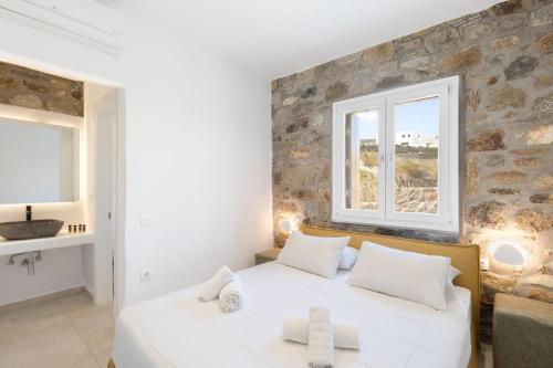 a bedroom with a white bed and two windows at ĪKADE Mykonos in Mýkonos City