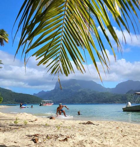 a man playing in the water on a beach at Studio bord de mer Fare Tahitea Pension in Taputapuapea
