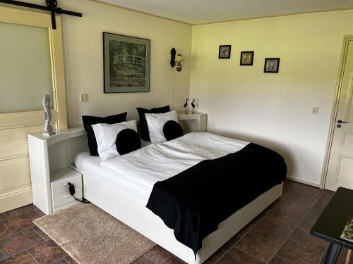 a bedroom with a white bed with black and white pillows at B&B De Handwijzer Hengelo in Hengelo