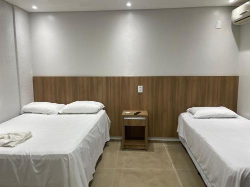 a room with two beds and a small table between them at Maxi Palace hotel in Capitão Leônidas Marques