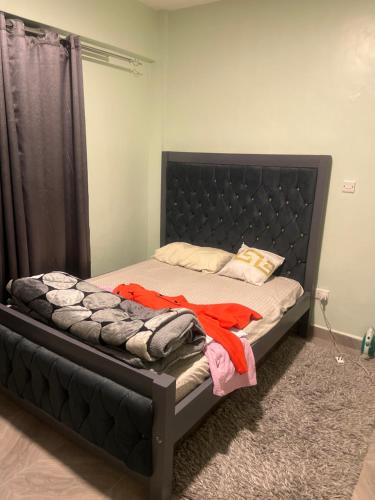 Bett mit schwarzem Kopfteil in einem Zimmer in der Unterkunft Trishas in Bungoma