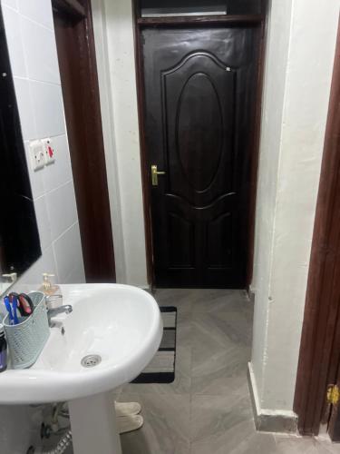 baño con lavabo y puerta negra en Trishas, en Bungoma