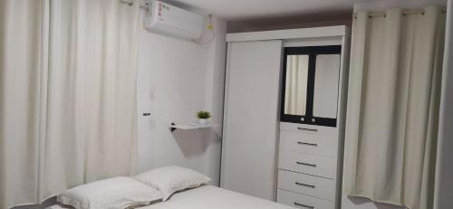 a bedroom with a bed and a dresser with a mirror at Praia do Caribessa - Quarto Privativo - Pedacinho do Paraíso in João Pessoa