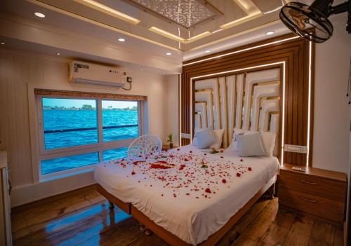 a bedroom with a large bed with red rose petals on it at Alice Houseboats Alleppey in Alleppey