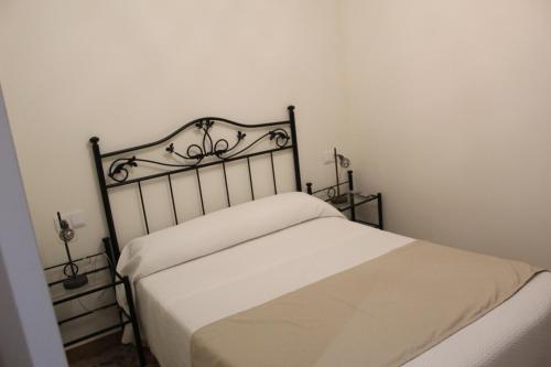 a bedroom with a white bed with a metal headboard at Alojamiento Rural La Estrella de David in Almagro
