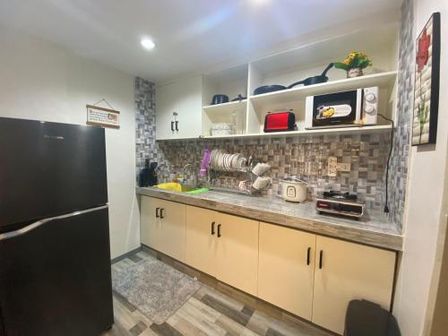 a kitchen with a black refrigerator and brown cabinets at Kege's Pad - 2 Bedroom Townhouse near Clark Airport & Aqua Planet - TRP8 in Mining