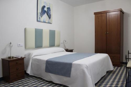 1 dormitorio con 1 cama y armario de madera en Alojamiento Rural La Estrella de David, en Almagro