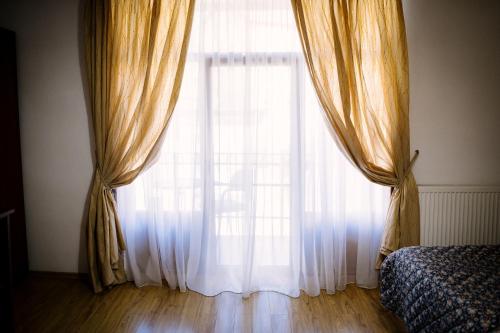 a window with curtains and a bed in a room at Class in Petroşani