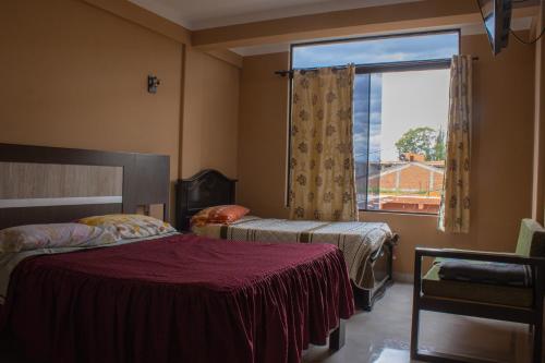 a bedroom with two beds and a large window at Residencial Tablada in Tarija