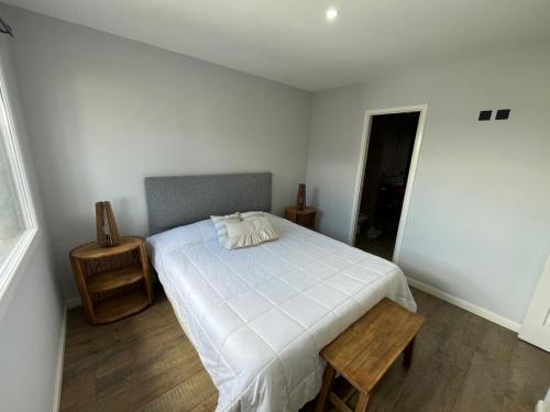 um quarto com uma cama branca e uma mesa de madeira em Departamento centrico vistas a la montaña em San Carlos de Bariloche