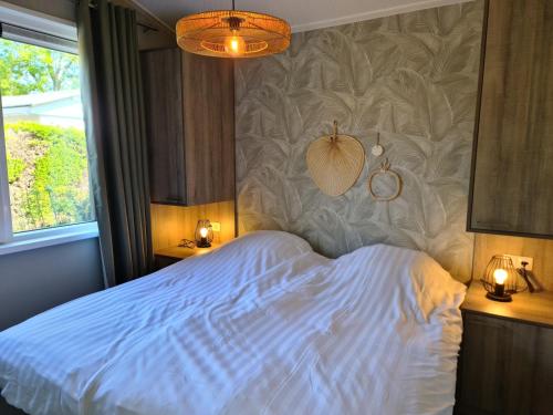 Un dormitorio con una cama blanca con dos luces. en Bungalowpark Mooyeveld, en Egmond-Binnen