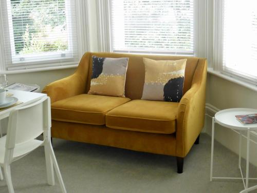 a yellow couch sitting in a living room with windows at Stylish studio apartment in central Hove. in Brighton & Hove