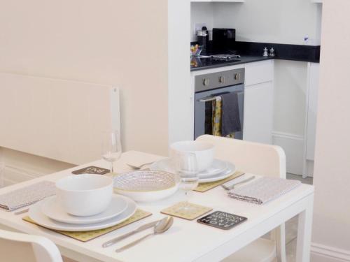 a white dining room table with white dishes on it at Stylish studio apartment in central Hove. in Brighton & Hove