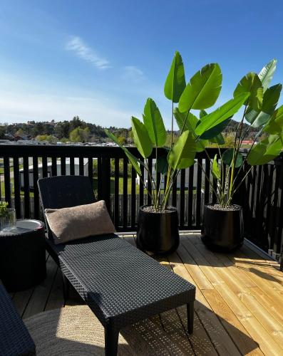 a balcony with two potted plants and a bench at experience a fantastic summer house 2025 in Kristiansand