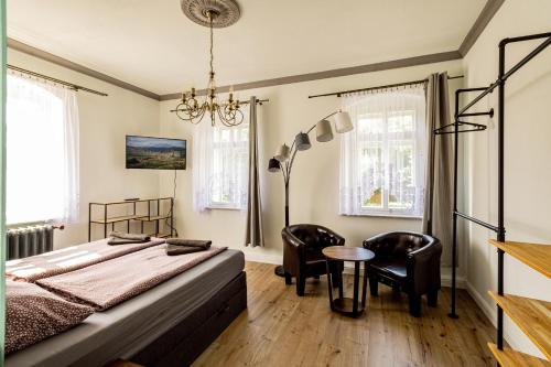 Villa Hänsch Suite 1 في غروسشوناو: غرفة نوم بسرير وكراسي وطاولة