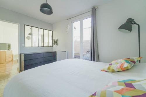 um quarto com uma grande cama branca e uma janela em Quiet cosy and large apartment with Terrace Top location em Saint-Ouen